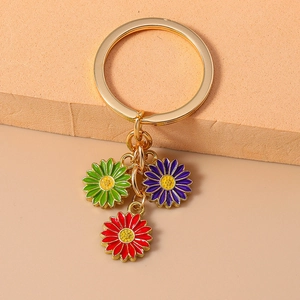 Detail of metal keychain with green red and purple enamel daisy flower charms
