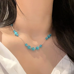 Détail d'un collier de perles œil-de-chat bleu sur un mannequin pour un look d'été
