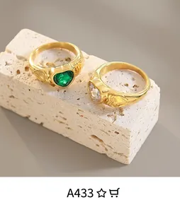 Close-up of vintage gold rings with heart-shaped green and white gems on stone