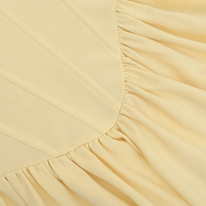 Close-up of cream yellow halter dress showing fine pleated texture and reinforced seams