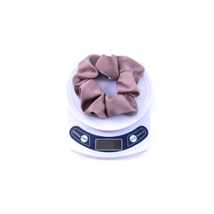 Close-up of a large purple satin scrunchie on a digital scale weighing about 7.5 grams