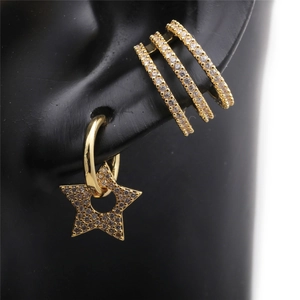 Detail of gold huggie hoop earrings and hollow star charm with zircon on ear model
