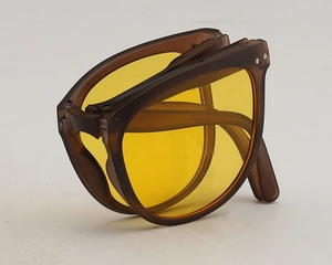 Close-up of portable folding sunglasses with matte brown frame and yellow lenses