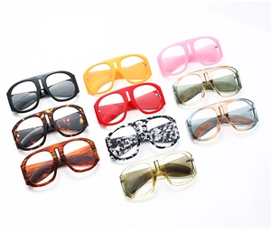 Flat lay of retro oversized sunglasses in ten colorful finishes on white background