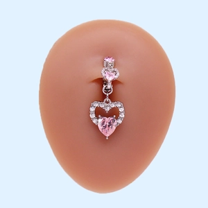 Detail of silver heart belly button ring with pink stones on a silicone navel model