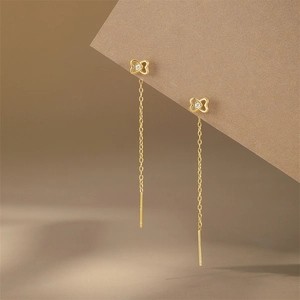 Close-up of golden long tassel ear thread with hollow bow design and white zircon
