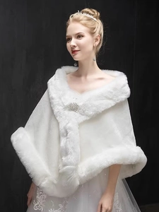 Close-up of white faux fur bridal shawl featuring an elegant decorative brooch detail
