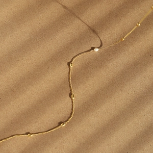 Macro detail of 18K gold plated chain necklace with delicate freshwater pearl accents