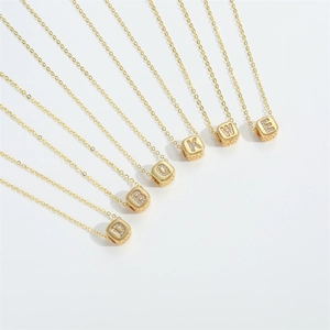 Macro detail of golden cube pendants with inlaid crystals on a minimalist chain