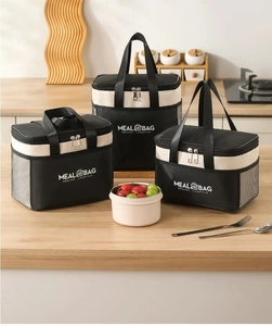 Three-piece insulated lunch bag set in black and beige canvas on a kitchen counter