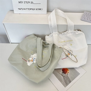 Detail of light green and white canvas tote bags with cute puppy embroidery and drawstring