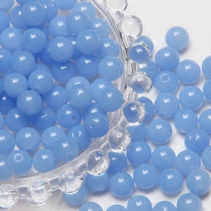 Close-up of 8mm light blue frosted glass beads scattered around a decorative bowl