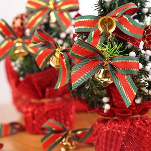 Close-up of mini Christmas tree decorations with red bow and gold bell detail