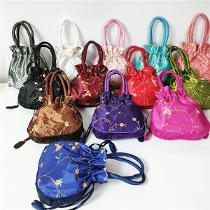 Detailed view of colorful embroidered satin drawstring bags with traditional floral patterns