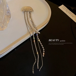 Silver jellyfish brooch with long pearl tassels and rhinestones on a white plate