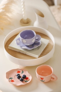 Detail of cute flower hand-painted ceramic coffee cup and saucer set with wooden tray