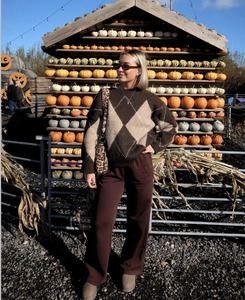 Detail of a brown argyle knit sweater with high-waisted wide-leg trousers for autumn