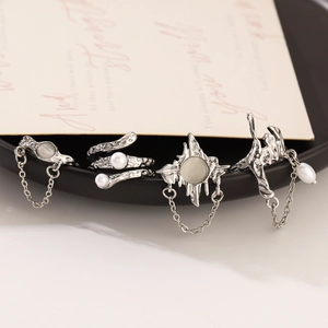 Detail of silver alloy ring set with star motifs, pearls and moonstone on black display