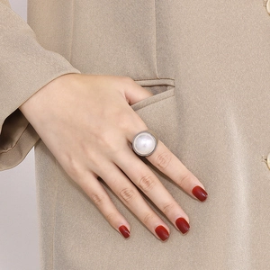 Détail d'une bague large en acier inoxydable argenté avec une grande perle blanche
