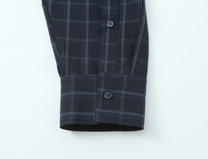 Detail of dark blue plaid poplin shirt cuff with precise stitching and round button