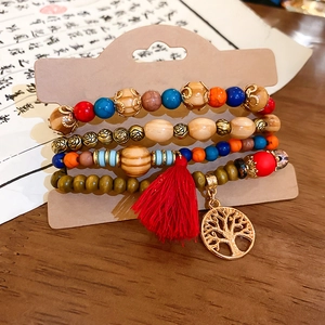 Detail of bohemian multilayer sandalwood beaded bracelet with tree of life charm and red tassel