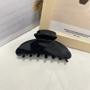 Glossy black acetate shark hair claw clip for women ponytail on minimalist background