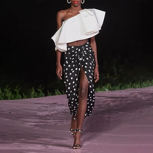 Detail of white one-shoulder ruffle top and high-waist polka dot wrap skirt with side slit