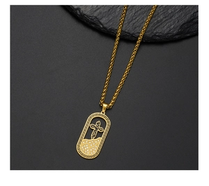 Macro detail of 18K gold-plated cross pendant with Greek key pattern and crystals