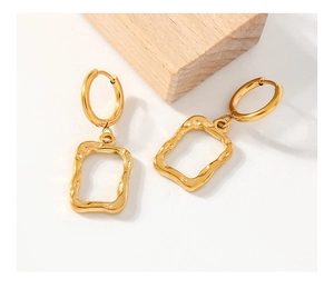 Detail view of gold stainless steel earrings with hammer texture and rectangular pendants