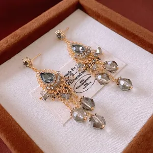 Bohemian gold tassel drop earrings featuring grey faceted crystals and sparkling pavé accents