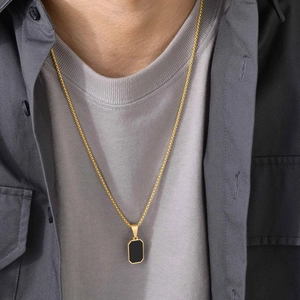 Men's gold necklace with a black rectangular pendant on a model in a high-quality view