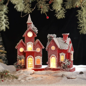 Red wooden Christmas cabins with white snow roofs and warm LED lights on black background