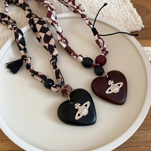 Detail of vintage wooden bead necklace featuring a heart pendant and silk scarf chain