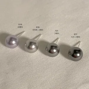 Macro detail of 925 silver pearl earrings in lavender, light grey, and dark grey tones