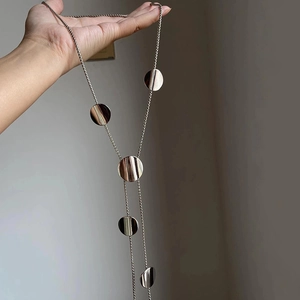 Polished silver geometric round pendant long tassel necklace held by hand for women