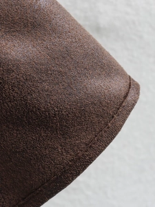 Detailed macro view of dark brown suede jacket texture with high-quality edge stitching