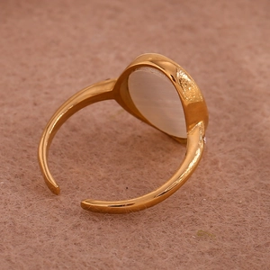 Detail of 18K gold-plated celestial ring featuring a white cat's eye stone on pink felt