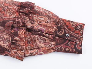 Detail of bohemian paisley chiffon shirt cuff with rich russet tones and button closure