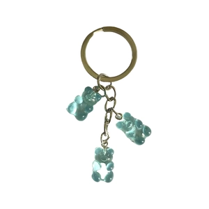 Translucent blue resin bear charms on a golden metal keychain with studio lighting