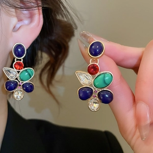 Detailed shot of vintage gold earrings with blue, red, and green teardrop crystal stones