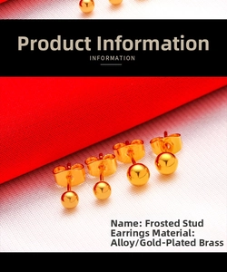 Detail of polished gold ball stud earrings with glossy finish on textured red background