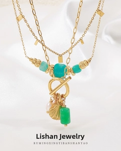 Dettaglio collana multistrato in ottone placcato oro 18K con pietre turchesi e conchiglia