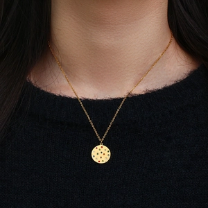 Close-up of golden necklace with colorful zircon gemstones on a round pendant