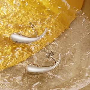Close-up of silver geometric teardrop earrings on amber glass with butterfly backings