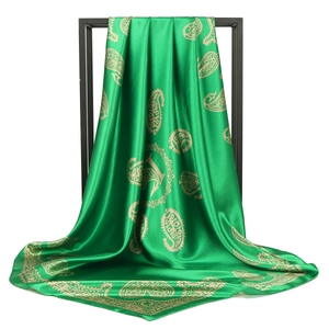 Detail of green paisley satin scarf with silky texture draped on a black metal frame