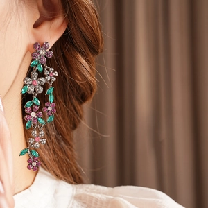 Gros plan de boucles d'oreilles vintage à fleurs et pompons portées par un mannequin