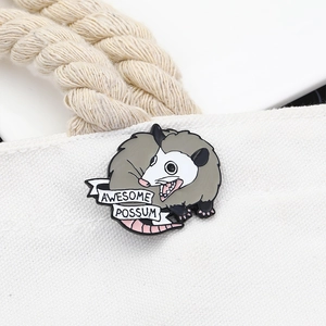 Enamel opossum brooch with Awesome Possum banner pinned on a white canvas bag
