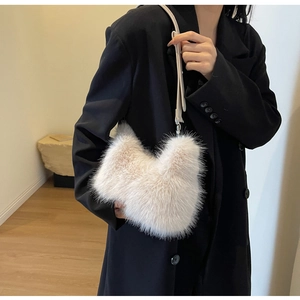 Detail of a plush cream faux fur shoulder bag with soft texture and slim leather strap