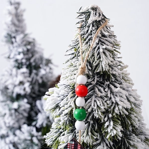 Christmas wooden bead garland with red and green buffalo plaid on snowy tree branch