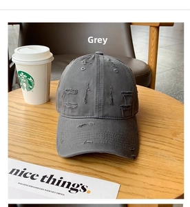 Close-up of distressed grey baseball cap with vintage rips and holes on a wooden table